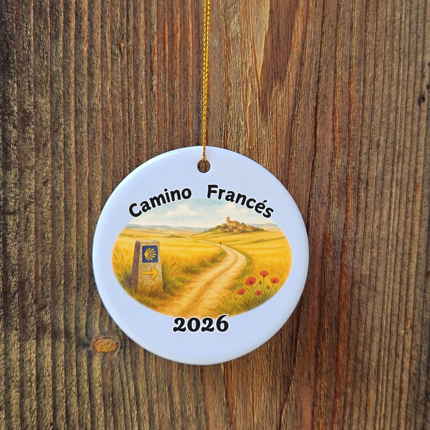Round ceramic ornament with 'Camino Francés' design and year 2026 on a wooden background