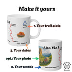 Mockup of the customizable Alta Via 1 mug with labels showing where you can add your distance, your travel dates, and your own words below the watercolor scene.