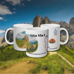 Product presentation of the Alta Via 1 hiking mug with Dolomites landscape illustration. Three mugs show front, back, and side views with personalized details in German.