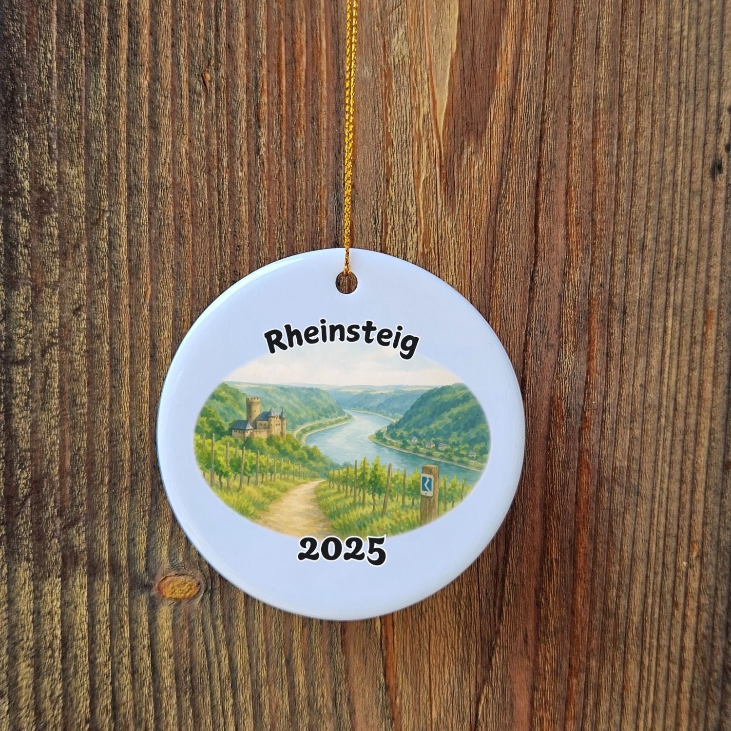 Ceramic ornament featuring a vineyard view of the Rheinsteig trail with the year 2025, displayed on rustic wood.