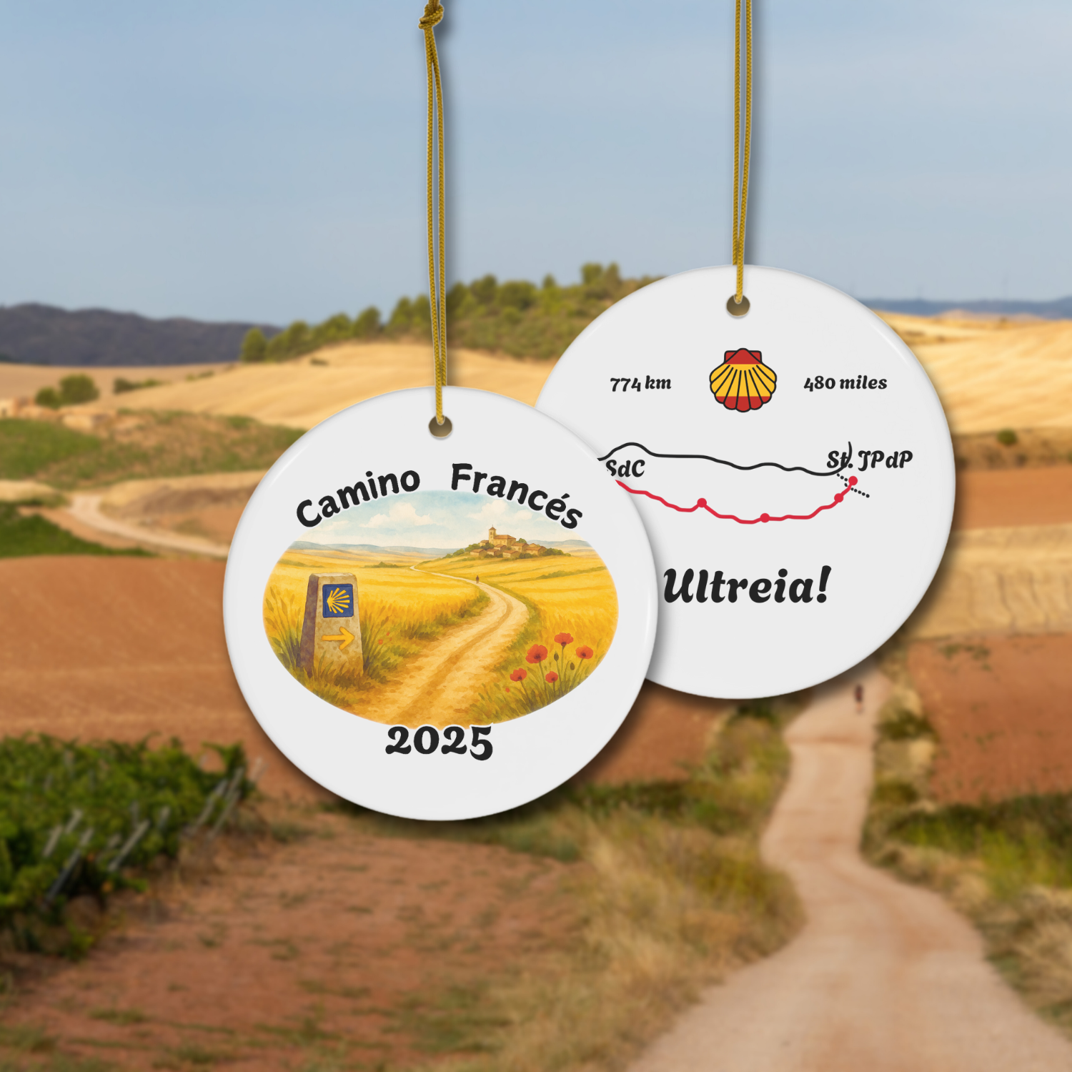 Camino Francés ceramic keepsake ornament with watercolor front and stylized map back, hanging on gold cord, shown against the Camino trail. Perfect gift for pilgrims, year customizable.
